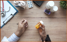Mão com frasco de comprimidos na mesa